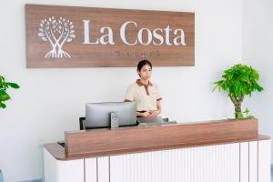 Una donna in piedi dietro un bancone con un portatile di La Costa Resort Quy Nhon a Quy Nhon Altre 44 foto