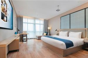 a hotel room with a large bed and a desk at Echarm Hotel Liuzhou Liunan Wanda Plaza in Liuzhou