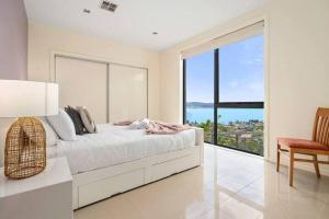 サンディ・ベイにあるThe View Luxury home 6 bed 4 bathのベッドと大きな窓のある白い寝室