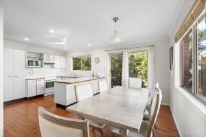 eine weiße Küche mit einem Tisch und Stühlen in der Unterkunft 26 Gannet Street, Peregian Beach in Peregian Beach