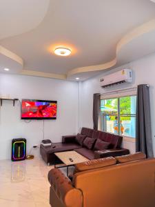 a living room with a couch and a flat screen tv at BAN SINGH TO Poolvilla in Cha Am +25 photos