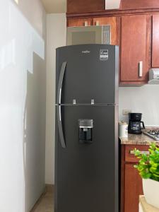 a black refrigerator in a kitchen with wooden cabinets at Descanso Frente al Consulado in Hermosillo