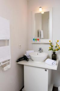 a white bathroom with a sink and a mirror at Ténéo Apparthôtel Bordeaux Maritime - Cité du vin in Bordeaux