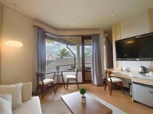 巴图KLUB BUNGA THEME PARK HOTEL的客厅里有一张沙发、一张桌子和几把椅子