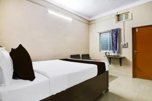 BhetiaSuper Collection O NIT More Adityapur Formerly Hotel Subheksha的一间卧室，里面有一张床、一张桌子和一扇窗户