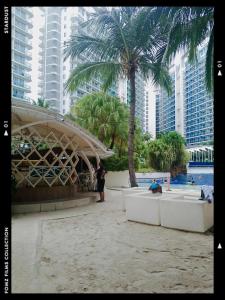 a person standing on a beach next to a palm tree at Azure Staycationcation by Nairah in Manila