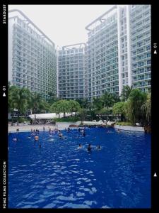 people swimming in a large pool in front of buildings at Azure Staycationcation by Nairah in Manila