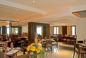 a restaurant with tables and chairs and flowers on tables at Shantai Hotel in Pune