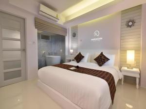 a white bedroom with a large bed and a bathroom at NanNakara Boutique Hotel in Nan