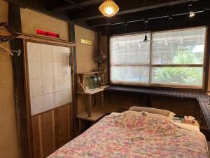 a bedroom with a bed and a window at 木古里ゲストハウス Kicoli guesthouse in Chizu