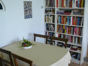 a table with chairs and a book shelf with books at De Bekboer in Losser