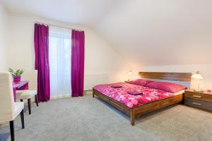 um quarto com uma cama, uma secretária e cortinas roxas em Aparmány² em Frymburk