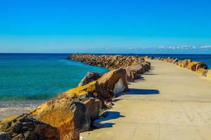 a walkway on the beach with rocks and the ocean at Barefoot at Blacksmiths Beach in Blacksmiths
