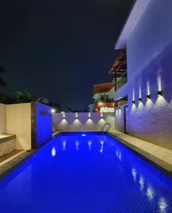 a blue swimming pool at night with a building at 3 BHK Mount Villa by Asmeera Stays in Lonavala