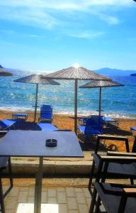 una mesa, sillas y sombrillas en una playa en Athena Apartment, en Nea Peramos