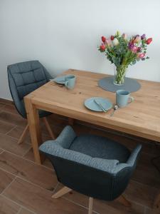 a wooden table with a vase of flowers and two chairs at Ferienhaus Hofmann Strüth 7 in Röttingen