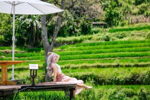 een pop die op een tafel onder een parasol zit bij MT House With Mountain View - Sa Pa Trekking Tour in Sa Pa