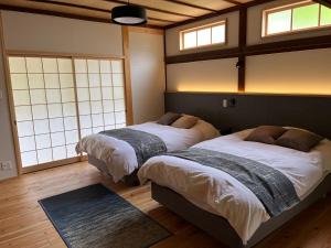 飞鸟まほろの宿 - 明日香村のリノベーション古民家一棟貸し的有两张床的房间有两扇窗户