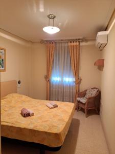 a bedroom with a bed and a chair and a window at Mon petit paradis à Albir in L’Alfàs del Pi