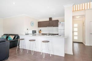 una cucina con bancone e bar con sgabelli di Maggies Beach House - Relaxed Stay Near the Beach a Broadwater