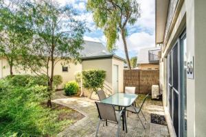 un patio con tavolo in vetro e sedie di Maggies Beach House - Relaxed Stay Near the Beach a Broadwater