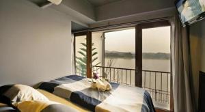 a bedroom with a balcony with a view of the water at Chic Chiangkhan Hotel in Chiang Khan