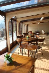 シャンペリーにあるホテル スイスの木製のテーブルと椅子、窓のあるレストラン