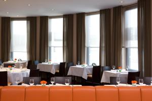 una sala da pranzo con tavoli, sedie e finestre di IntercityHotel Mainz a Magonza