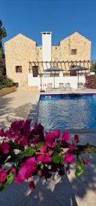 a pool with pink flowers in front of a building at Villa Penelope Luxury Retreat with Pool & Timeless Charm in Douliana