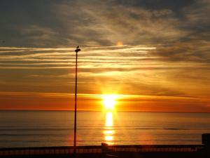 a sunset over the ocean with a street light at Hotel de la Plage - Barcares in Le Barcarès +29 photos