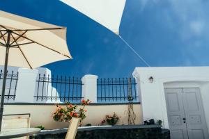 a white building with a blue sky and an umbrella at Day One Fira Mansion in Fira