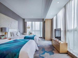 a hotel room with two beds and a flat screen tv at Shunshine International Hotel Xiangxi in Ganziping +245 photos