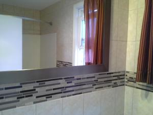 La salle de bains est pourvue d'un miroir et d'une fenêtre. dans l'établissement Budget Inn Tonawanda, à Tonawanda
