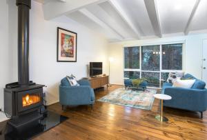 - un salon avec une cheminée et deux chaises bleues dans l'établissement Belle Cottage Secluded Stay Near Shops Cafes, à Sassafras