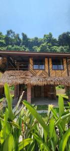 una casa con techo de paja en la selva en Bamboo Cottage Langkawi, en Pantai Cenang