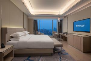 a hotel room with a bed and a flat screen tv at Wyndham Shaoxing Keqiao in Shaoxing +68 photos