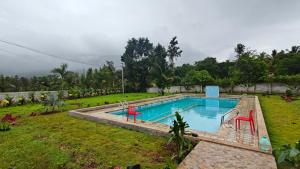 a swimming pool with red chairs in a yard at Golden Hill Resort in Chikmagalūr