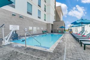 CoppellHome2 Suites by Hilton Coppell DFW Grapevine North的一个带椅子和遮阳伞的游泳池