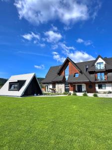a house with a green lawn in front of it at Hill House Apartamenty in Białka Tatrzanska