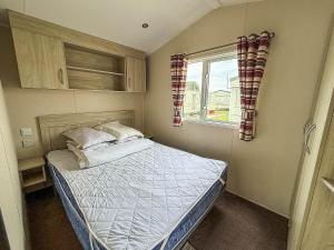 a small bedroom with a bed and a window at Lovely 6 Berth Caravan At Seawick Holiday Park In Essex Ref 27008S in Clacton-on-Sea +10 photos