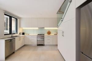 a kitchen with white cabinets and a large window at Spacious Surry Hills Home in Sydney