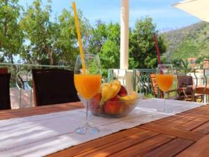 two glasses of orange juice and a bowl of fruit on a table at Apartments Seafront Silence - One Bedroom Apartment with Terrace and Sea View in Trstenik