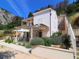a white house with a porch and some plants at Apartments Seafront Silence - One Bedroom Apartment with Terrace and Sea View in Trstenik