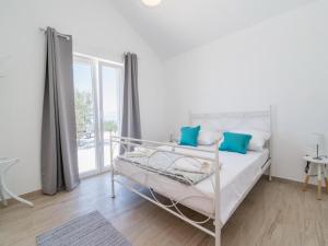 ein weißes Schlafzimmer mit einem Bett mit blauen Kissen in der Unterkunft Holiday Home My Summer House - Two-Bedroom Holiday Home with Private Pool and Terrace - ST in Supetar