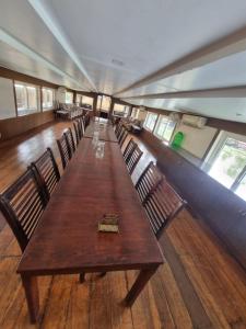 einen langen Holztisch und Stühle in einem Zimmer in der Unterkunft Lake Paradise Hoseboat in Alappuzha