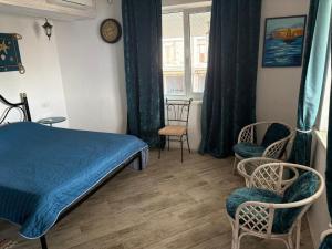 a bedroom with a bed and chairs and a window at Apartments Marine in Zatoka