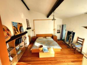 a bedroom with a large bed and wooden floors at Charming brickyard cottage near a lock in Ayguesvives