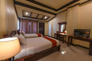 a bedroom with two beds and a flat screen tv at Pon Arena Hotel in Muang Không