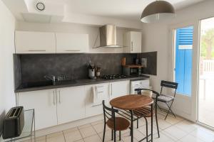 eine Küche mit weißen Schränken und einem Tisch und Stühlen in der Unterkunft La Maison du Bonheur & Escapade Côte Bleue in Martigues