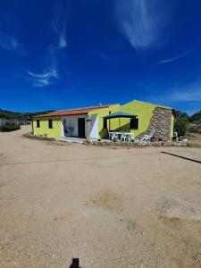 a yellow building with a table and chairs in front of it at B&B li salcuneddi in Aglientu